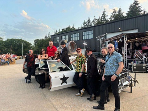 The eight-piece band gathered around the Bluesmobile